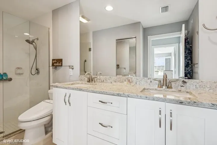 Bathroom featuring toilet, vanity, and a shower with door