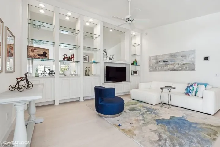 Living room with light wood-type flooring, built in shelves, and ceiling fan
