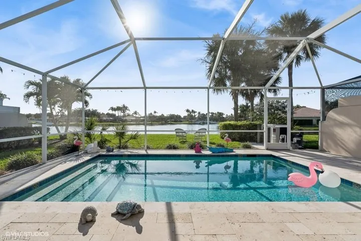 View of pool with a water view, glass enclosure, and a patio area