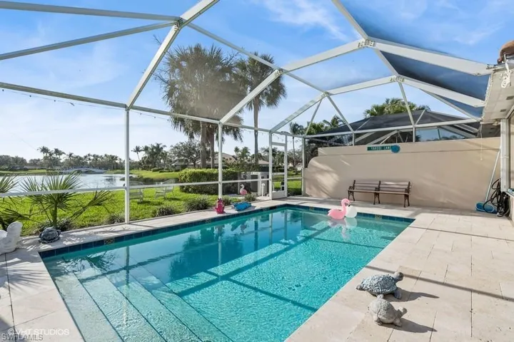 View of pool with a patio area and glass enclosure