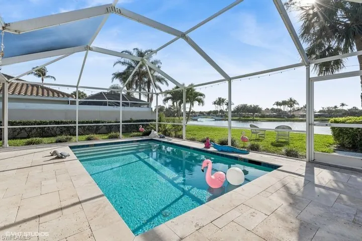 View of swimming pool featuring a patio, a water view, and glass enclosure