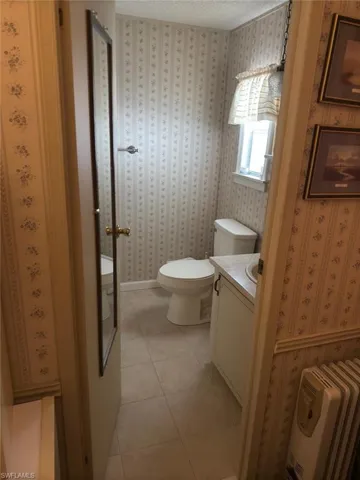 Bathroom featuring tile patterned floors, vanity, toilet, and a textured ceiling