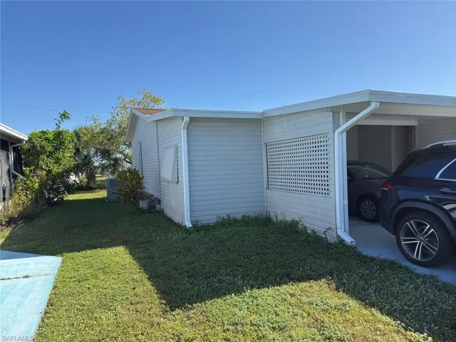 View of property exterior with a carport, a yard, and central AC