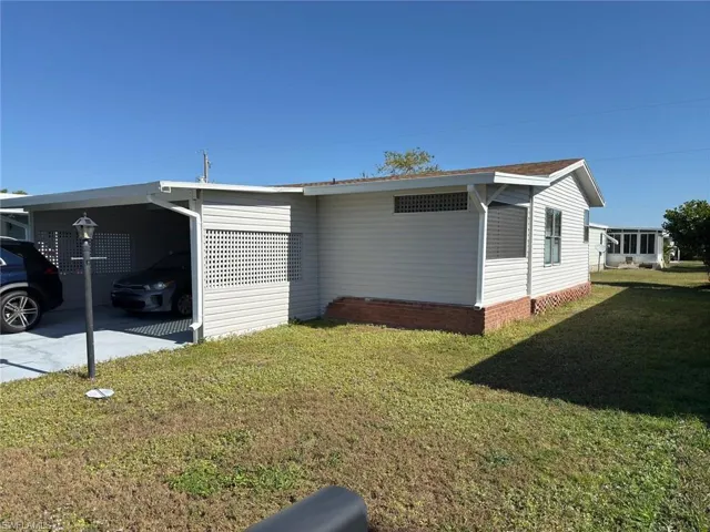 View of property exterior featuring a yard and a carport