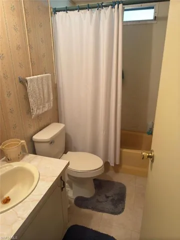 Full bathroom with toilet, vanity, tile patterned floors, and shower / bathtub combination with curtain