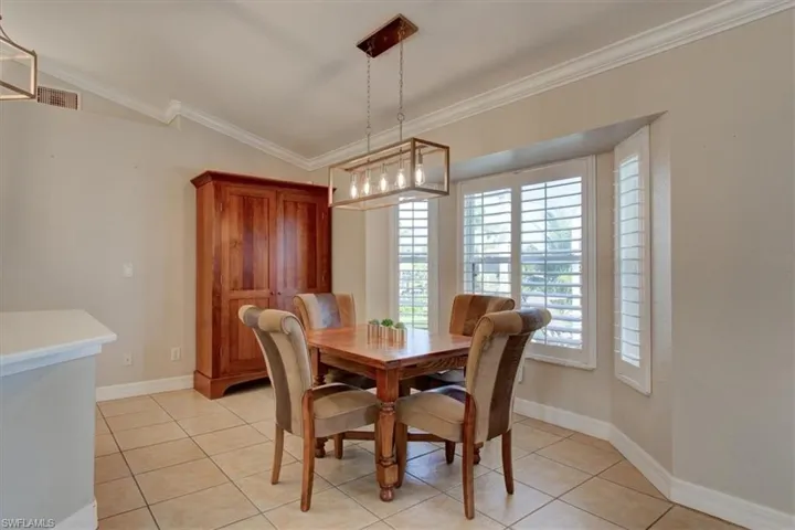 Dining space featuring ornamental molding, light tile patterned floors, and lofted ceiling