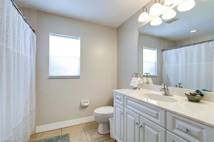 Bathroom with vanity, light tile patterned floors, and a shower with curtain
