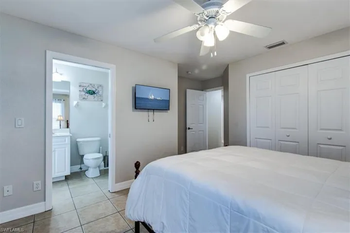 Bedroom with light tile patterned flooring, ceiling fan, a closet, and connected bathroom