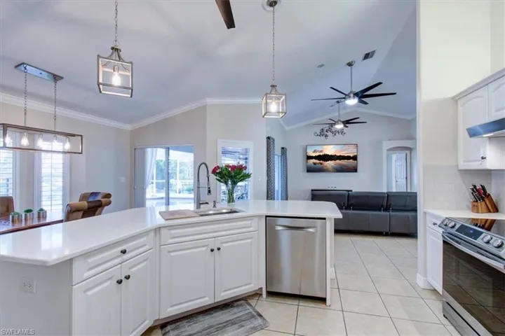 Kitchen featuring open floor plan, crown molding, decorative backsplash, stainless steel appliances, and white cabinets