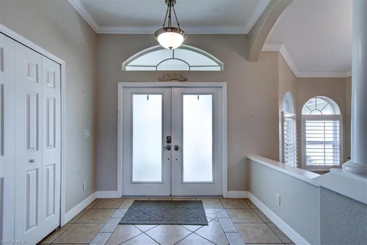 Foyer featuring french doors, ornamental molding, and arched transom above door.