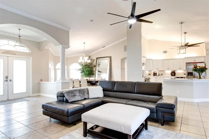 Living area with french doors, arched walkways, , high vaulted ceiling, and a chandelier
