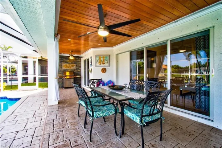 View of patio featuring a lanai, ceiling fan, covered lanai, outdoor dining space, and an outdoor pool