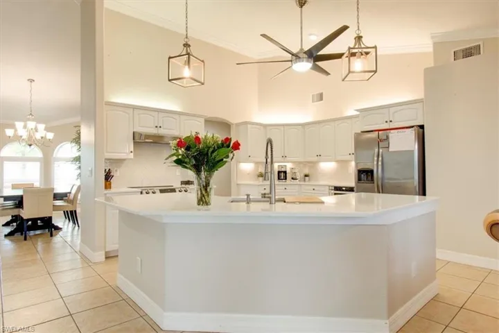 Kitchen with ornamental molding, quartz countertops, pendant lighting, backsplash, and a towering ceiling