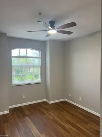 Empty room featuring dark wood finished floors, baseboards, and ceiling fan