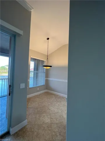 Tiled spare room featuring a healthy amount of sunlight, baseboards, and lofted ceiling
