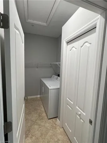 Laundry room with light tile patterned floors, baseboards, laundry area, and washing machine and clothes dryer