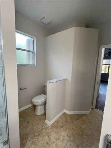 Bathroom with toilet, a healthy amount of sunlight, visible vents, and baseboards