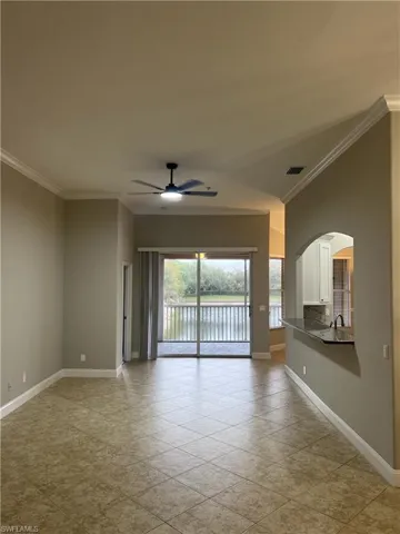 Unfurnished room with a water view, ornamental molding, arched walkways, baseboards, and ceiling fan