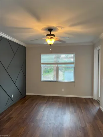 Unfurnished room with dark wood finished floors, a ceiling fan, baseboards, and ornamental molding