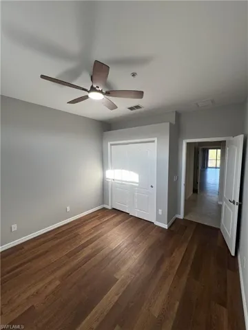 Unfurnished bedroom with dark wood finished floors, visible vents, ceiling fan, and baseboards