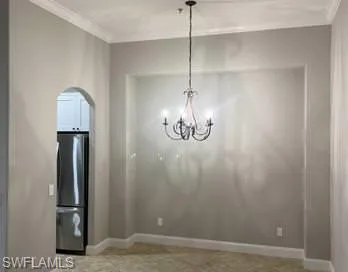 Unfurnished dining area with arched walkways, crown molding, and baseboards