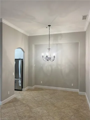 Unfurnished room featuring visible vents, baseboards, ornamental molding, and a chandelier