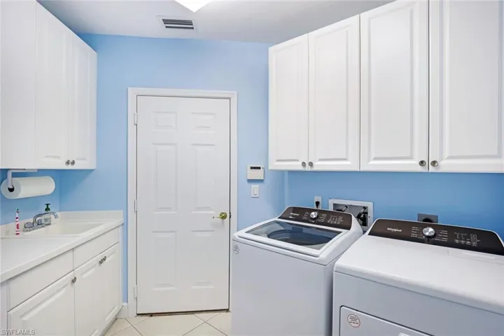 Spacious laundry room inside residence with sink and lots of cabinet space.