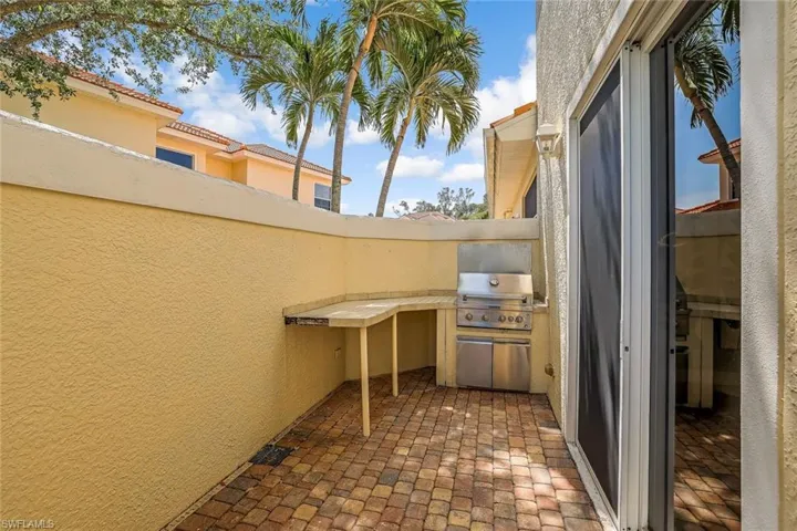 Side patio off of formal dining room and kitchen has a built-in grill and countertop.