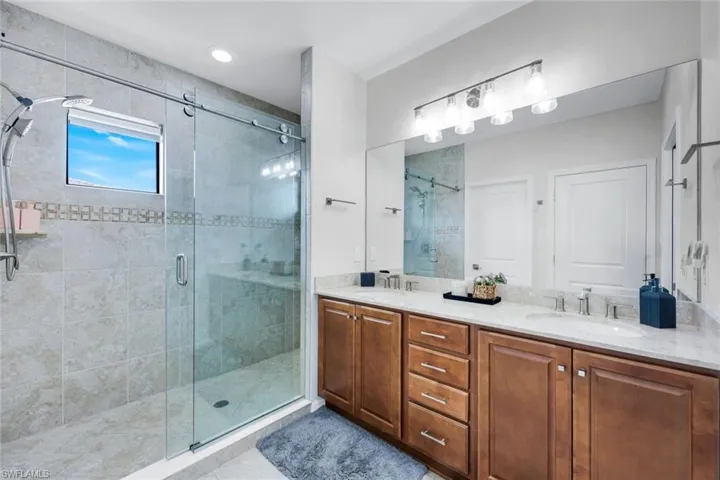 Full bathroom featuring a stall shower, double vanity, and light tile patterned floors