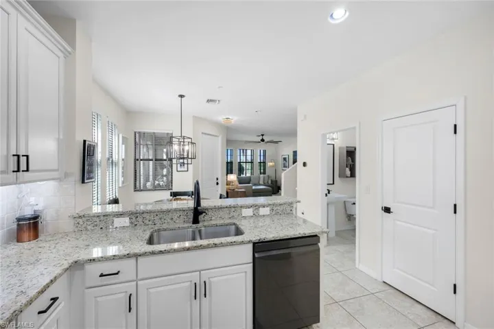 Kitchen with light stone counters, white cabinets, and a peninsula