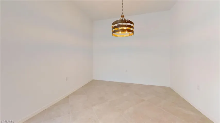 Spare room with suspended lighting and lofted ceiling