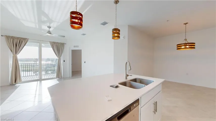 Kitchen featuring open floor plan, an island with sink, hanging light fixtures, and white cabinetry