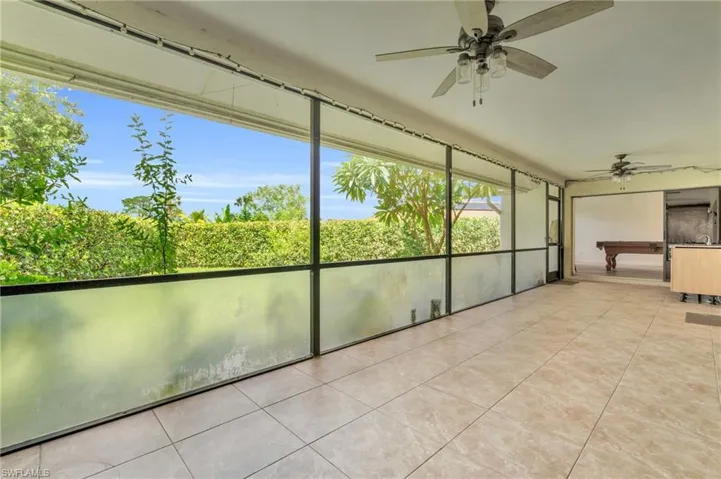 Unfurnished sunroom with ceiling fan and pool table