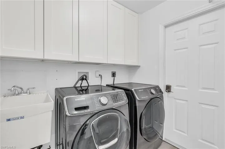 Laundry room featuring sink, washer and dryer, and cabinets