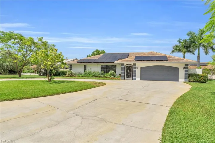 Ranch-style house with a front yard, solar panels, and a garage