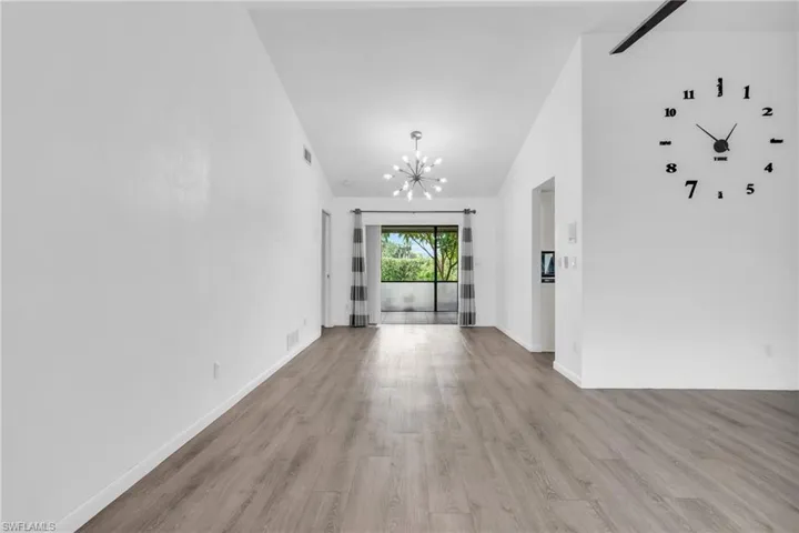 Spare room with high vaulted ceiling, a notable chandelier, and light hardwood / wood-style flooring