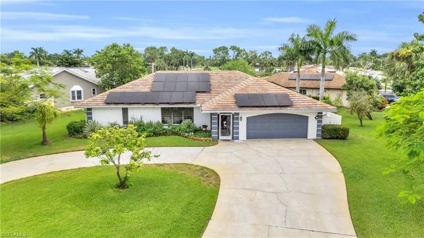 View of front of property featuring a front lawn, solar panels, and a garage