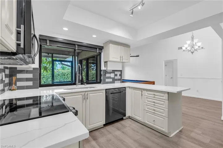 Kitchen with tasteful backsplash, white cabinetry, light hardwood / wood-style floors, kitchen peninsula, and stainless steel appliances
