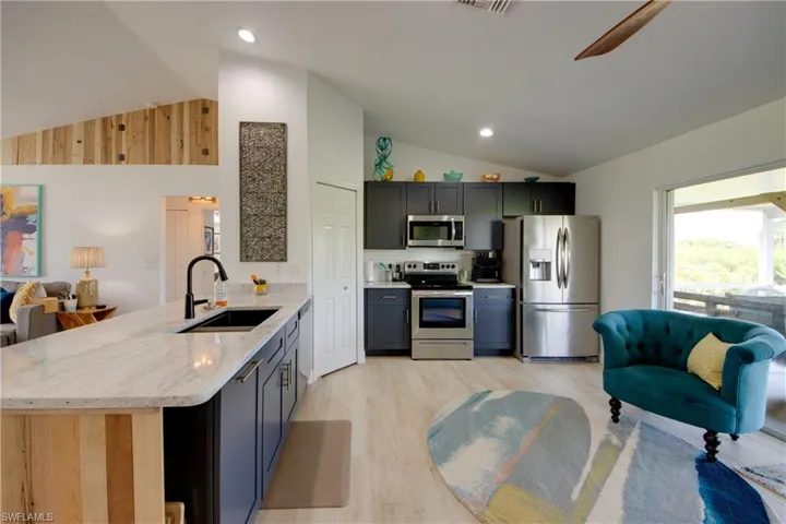 Kitchen featuring, high vaulted ceiling, custom cabinets, kitchen peninsula, sink, and appliances with stainless steel finishes