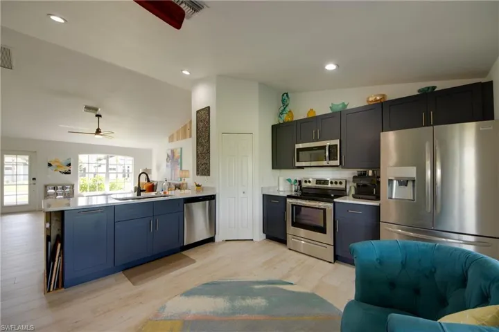 Kitchen with vaulted ceiling, kitchen peninsula, sink, ceiling fan, and appliances with stainless steel finishes