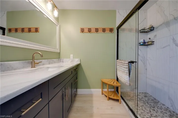 Bathroom featuring custom vanity, new tile shower with shower door