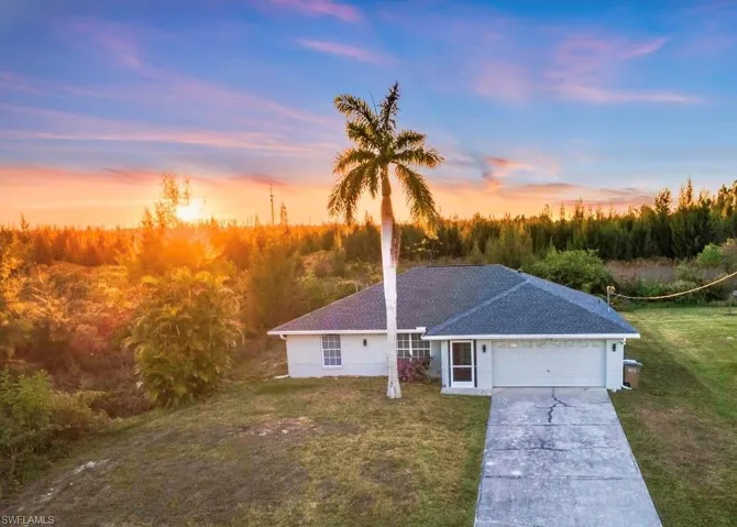 Ranch-style house featuring a front lawn, concrete driveway, an attached garage, and roof with shingles