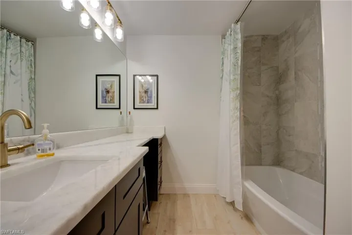 Bathroom featuring hardwood tile flooring, custom cabinets tub combo, and mew faucet