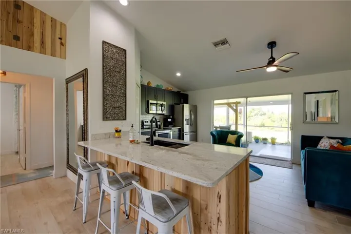 Kitchen featuring appliances with stainless steel finishes, light granite countertops, and ceiling fan