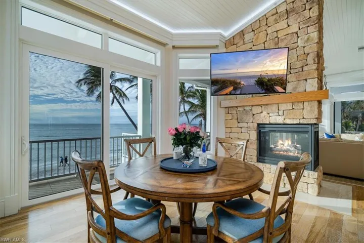 Dining space featuring wood ceiling, a stone fireplace, light hardwood / wood-style flooring, and ornamental molding
