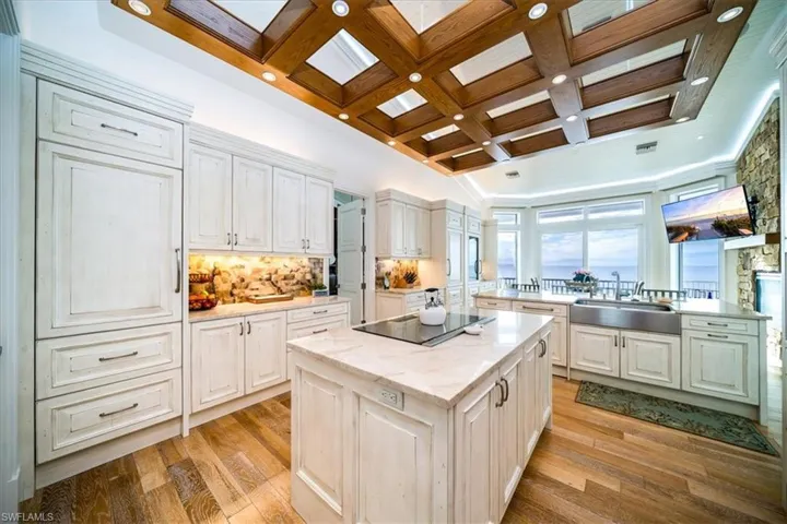 Kitchen featuring coffered ceiling, sink, white cabinetry, a center island, and black electric cooktop