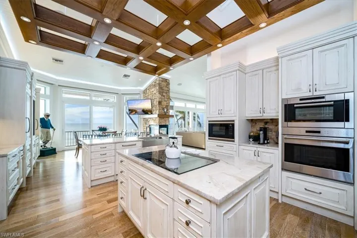 Kitchen with coffered ceiling, a center island, and white cabinets