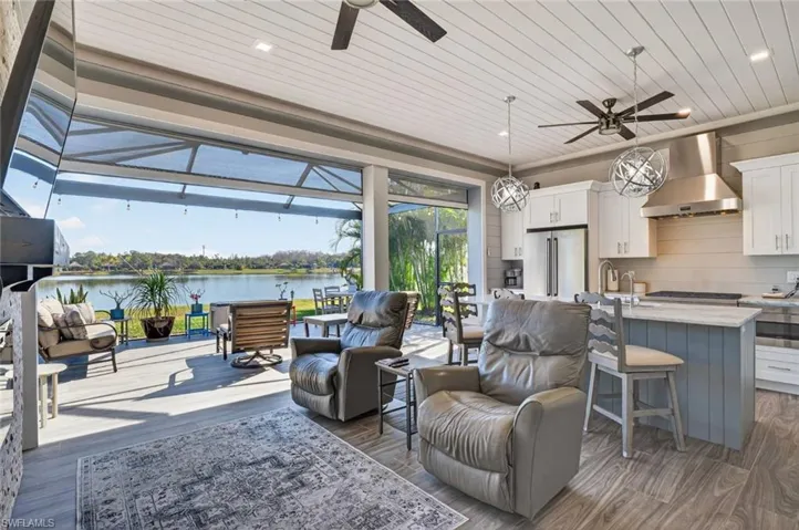 Living room featuring a sunroom, ceiling fan, dark wood-style flooring, wooden ceiling, and a water view