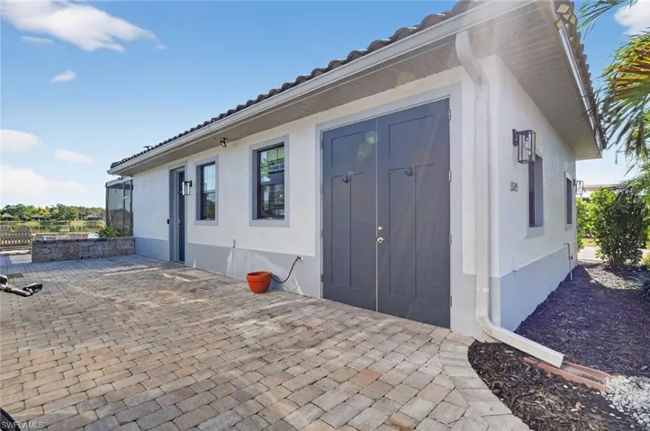 Doorway to property featuring stucco siding, a tile roof, and a patio area