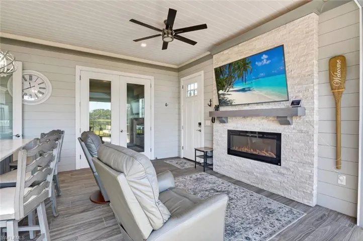 Wooden terrace featuring an outdoor stone fireplace, french doors, and ceiling fan